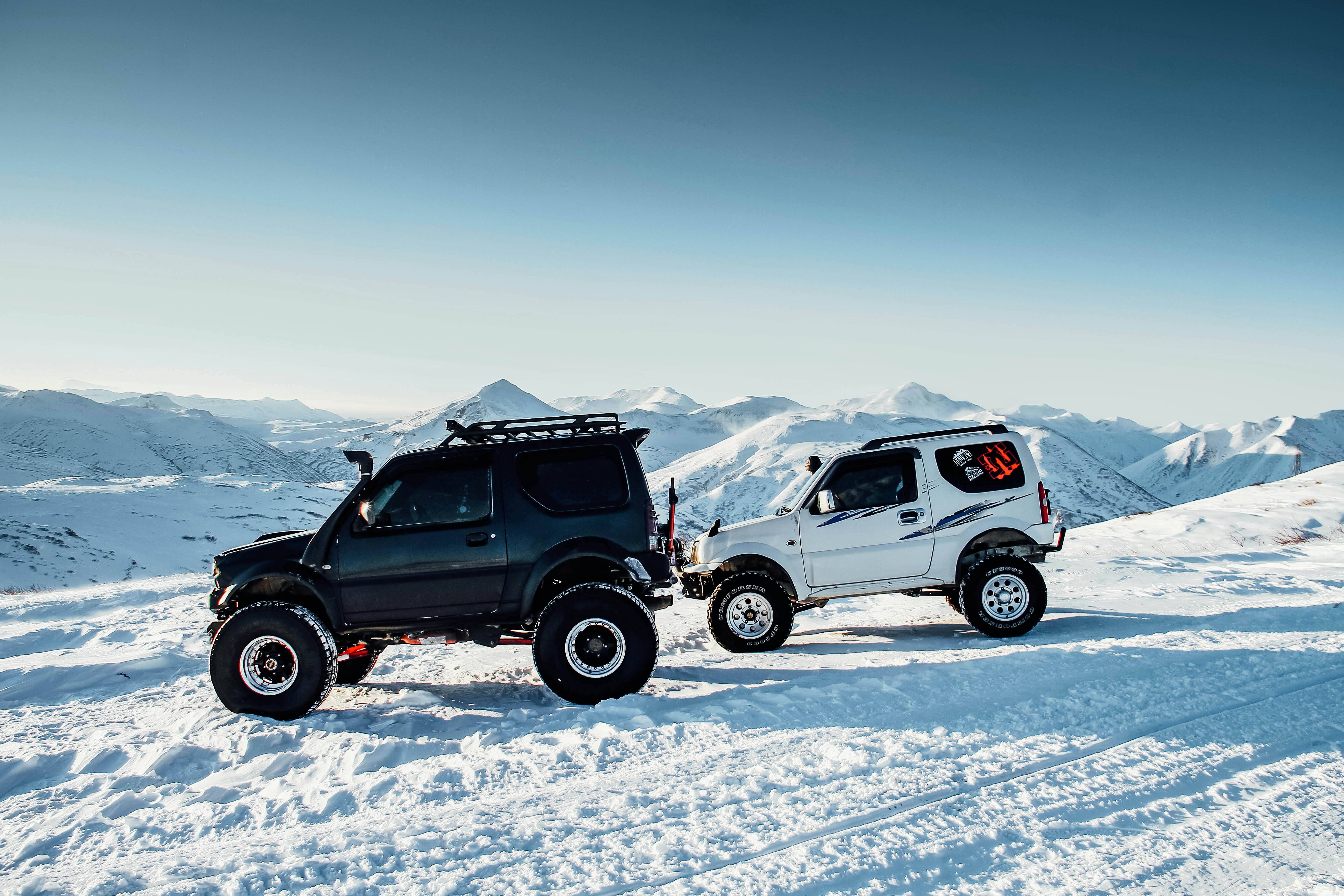 two white and black SUV on snow path